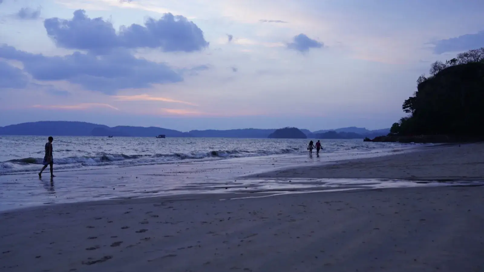 כביש החוף אל Ao Nang בשעת הזהב, מצוקי גיר מתרוממים מאחורי קימור של חוף ומוניות חולפות
