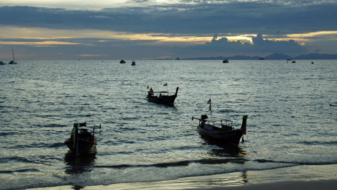 Longtail boats moored just off Ao Nang Beach at dusk, with the last light over the offshore islands