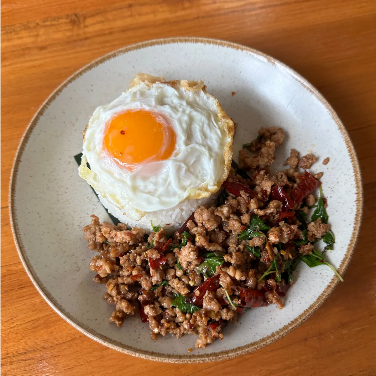 Pad kra pao — stir-fried minced pork with holy basil and chilli over rice, topped with a crispy fried egg